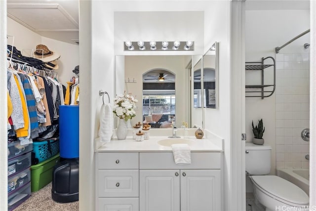 full bathroom featuring bathing tub / shower combination, a spacious closet, toilet, a ceiling fan, and vanity