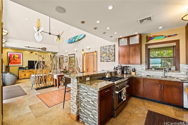 kitchen with stainless steel appliances, a peninsula, a sink, visible vents, and decorative backsplash