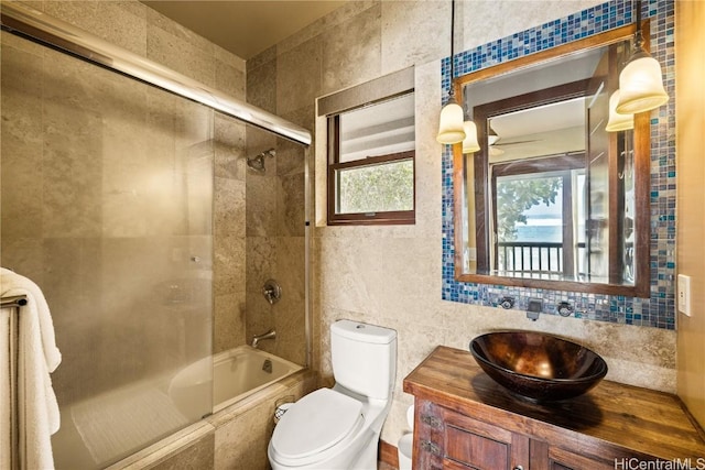 full bathroom featuring toilet, tiled shower / bath combo, vanity, tile walls, and backsplash