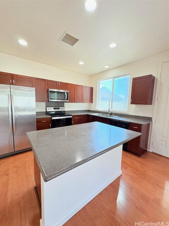 kitchen with a sink, stainless steel appliances, light wood-style floors, and visible vents