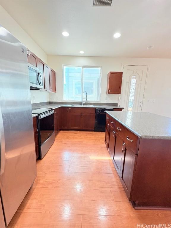 kitchen with light wood-type flooring, a sink, a kitchen island, recessed lighting, and stainless steel appliances