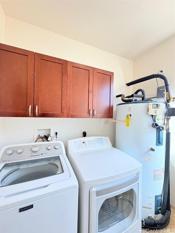 washroom with washer and dryer, cabinet space, and water heater