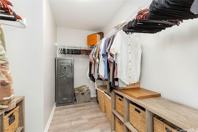 walk in closet with light wood finished floors