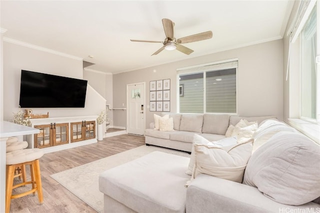 living room featuring wood finished floors, a ceiling fan, and ornamental molding