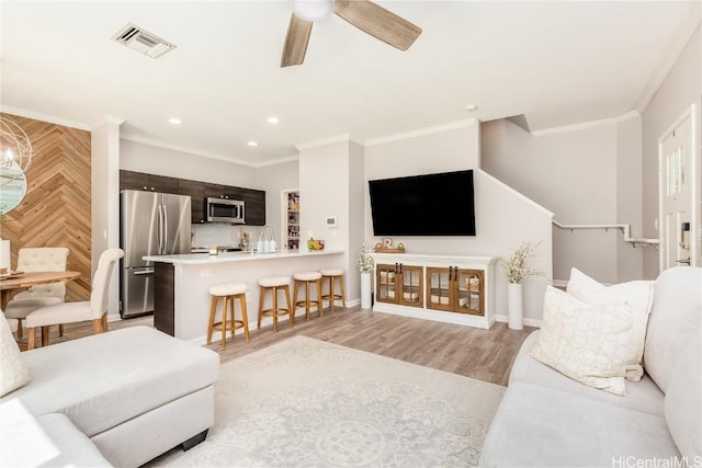 living area with visible vents, crown molding, and light wood finished floors