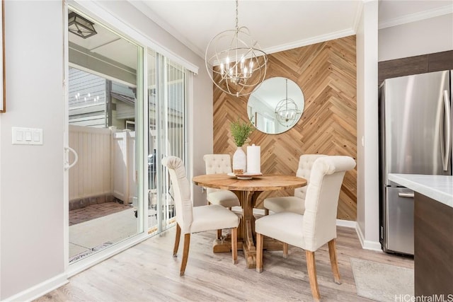 dining space with a notable chandelier, light wood-style flooring, and crown molding