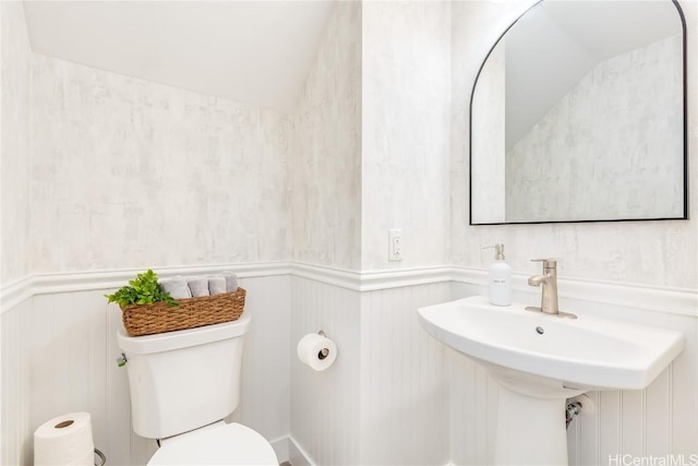 bathroom with lofted ceiling, toilet, and wainscoting