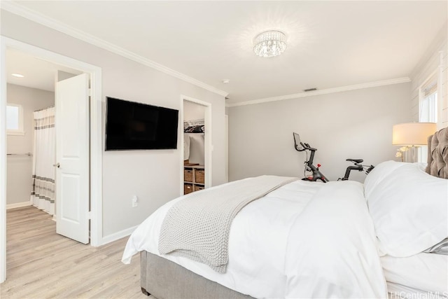 bedroom with visible vents, a walk in closet, light wood-style flooring, crown molding, and baseboards