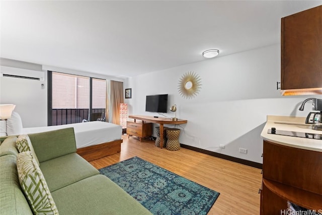 living area with a wall mounted air conditioner, light wood-style flooring, and baseboards