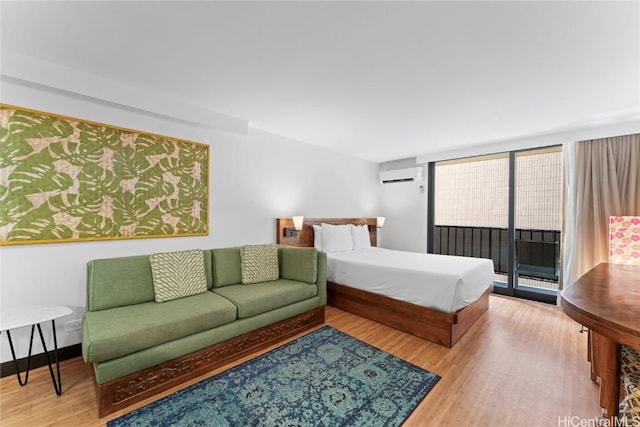 bedroom featuring baseboards, an AC wall unit, wood finished floors, and access to exterior