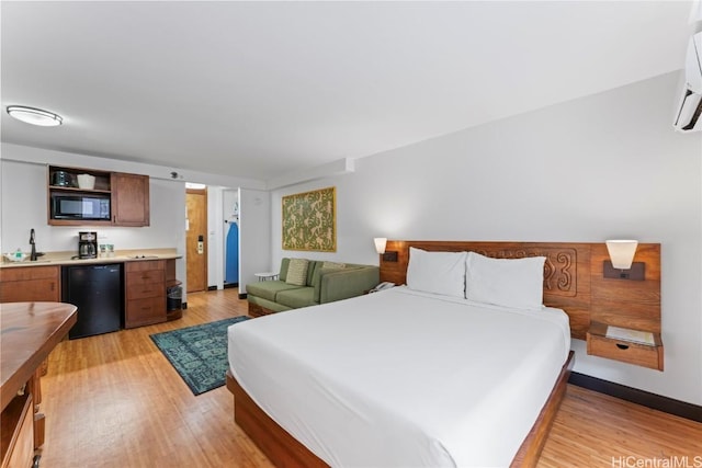 bedroom with baseboards, light wood finished floors, wet bar, and refrigerator