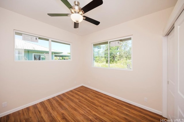 unfurnished bedroom featuring multiple windows, baseboards, and wood finished floors