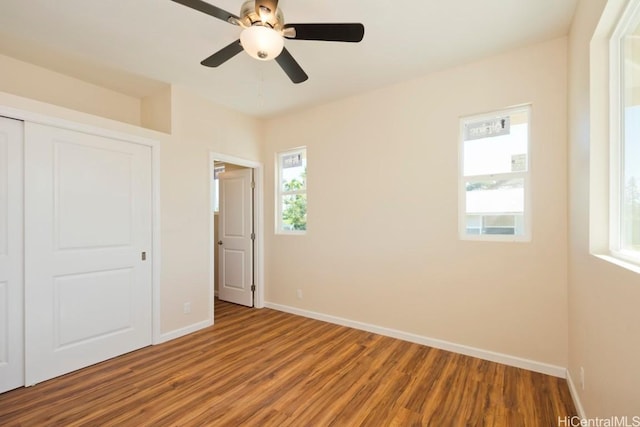 unfurnished bedroom featuring ceiling fan, a closet, baseboards, and wood finished floors