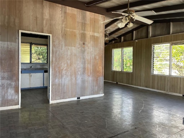 unfurnished room with vaulted ceiling with beams, wood walls, and baseboards