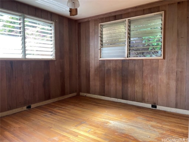 spare room featuring wooden walls, baseboards, and wood finished floors