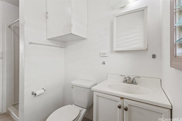 bathroom with a stall shower, toilet, and vanity