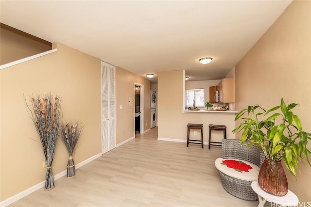 corridor with washer / clothes dryer, light wood-style flooring, and baseboards