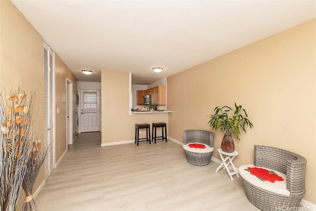 living area with light wood-type flooring and baseboards