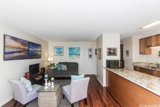 living area with a textured ceiling, dark wood-style flooring, and baseboards