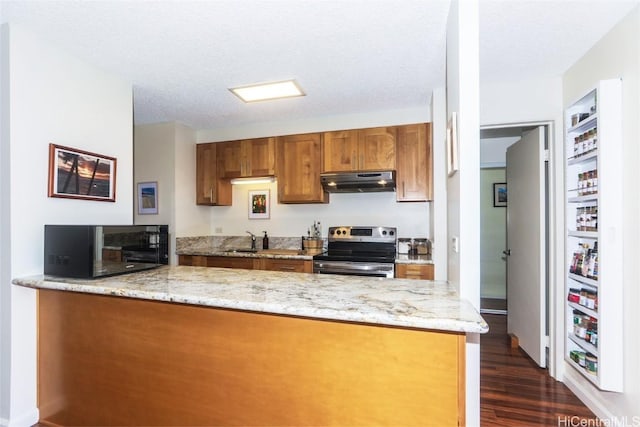 kitchen with electric range, brown cabinetry, a sink, a peninsula, and under cabinet range hood