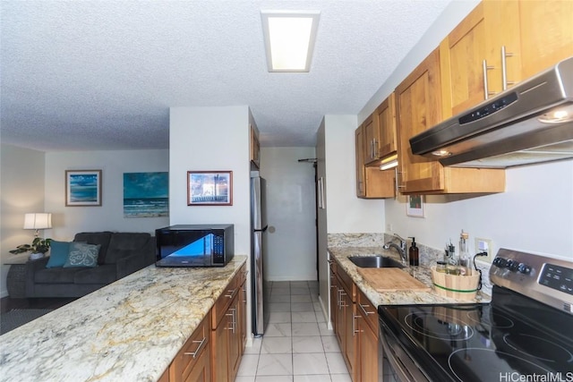 kitchen featuring brown cabinets, appliances with stainless steel finishes, a sink, and under cabinet range hood