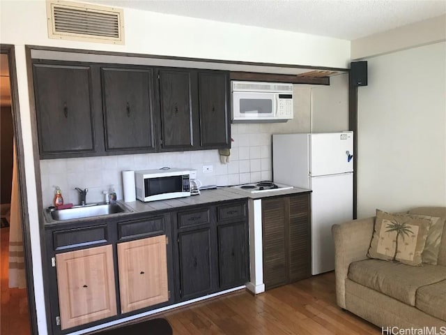 kitchen with tile countertops, tasteful backsplash, visible vents, a sink, and white appliances