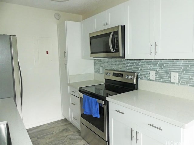 kitchen with white cabinets, stainless steel appliances, backsplash, and light countertops