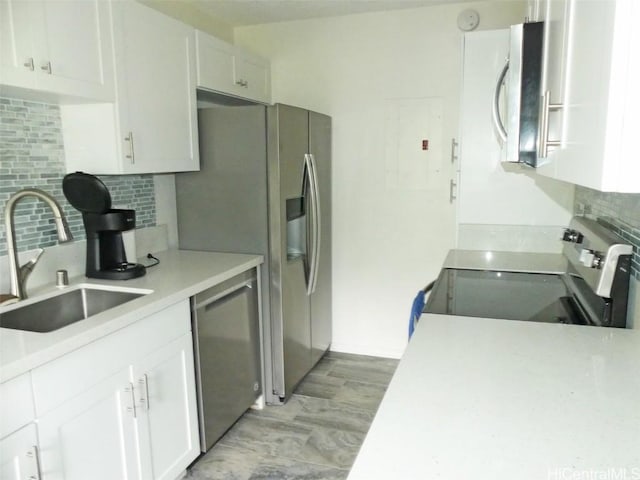 kitchen featuring appliances with stainless steel finishes, decorative backsplash, a sink, and white cabinets