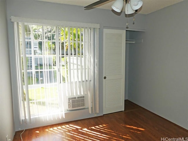 interior space featuring a ceiling fan, cooling unit, and wood finished floors