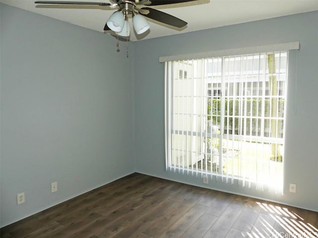 spare room with dark wood-type flooring, plenty of natural light, and a ceiling fan