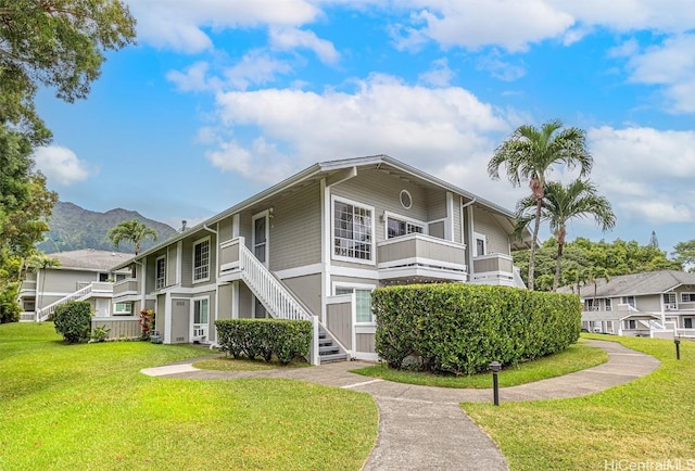 townhome / multi-family property with a balcony, stairs, a mountain view, and a front lawn