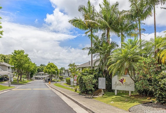 view of road with sidewalks, a residential view, a gated entry, and curbs