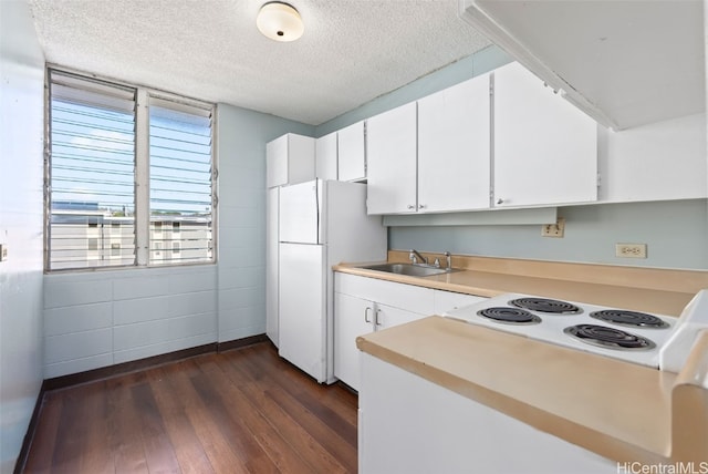 kitchen with dark wood finished floors, freestanding refrigerator, a textured ceiling, stovetop, and a sink
