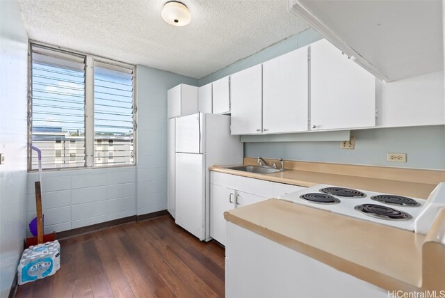 kitchen with a textured ceiling, a sink, freestanding refrigerator, dark wood-style floors, and stovetop