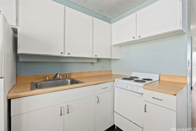 kitchen with a textured ceiling, light countertops, white appliances, and a sink