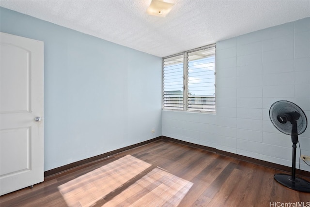 empty room featuring dark wood-style floors, a textured ceiling, and baseboards
