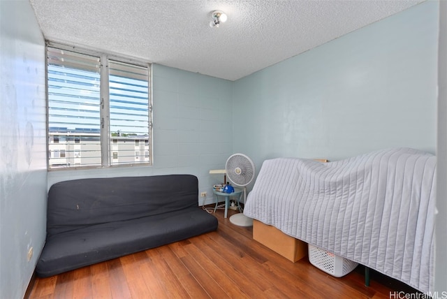 bedroom with a textured ceiling and wood finished floors