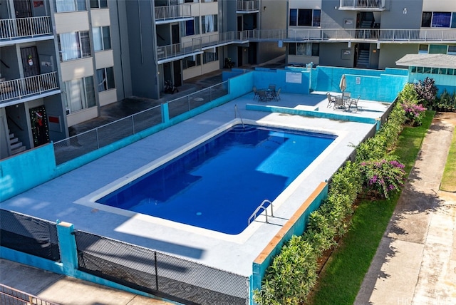 view of swimming pool with a patio and fence