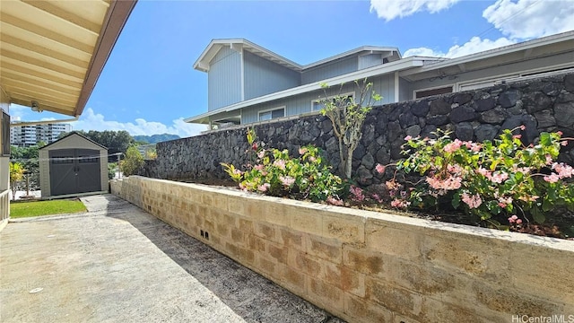 view of patio with an outbuilding, fence, and a storage shed