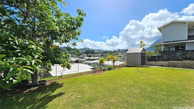 view of yard featuring a fenced backyard, a storage unit, a mountain view, and an outdoor structure