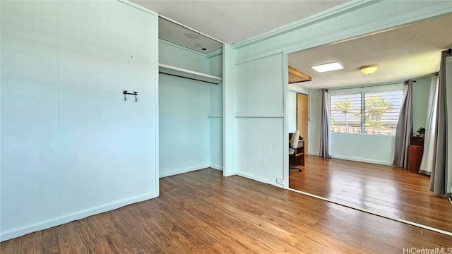 unfurnished bedroom featuring a closet, baseboards, and wood finished floors