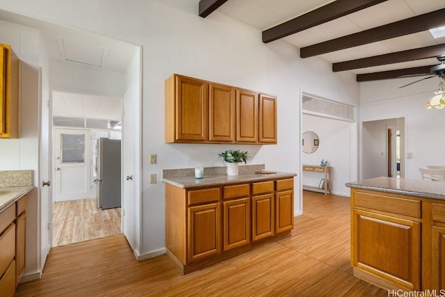 kitchen featuring brown cabinets, freestanding refrigerator, ceiling fan, light wood-type flooring, and beamed ceiling