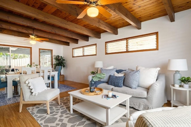 living area featuring light wood finished floors, wood ceiling, a ceiling fan, and beamed ceiling