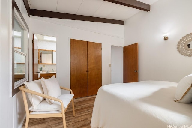 bedroom with a closet, beamed ceiling, and wood finished floors