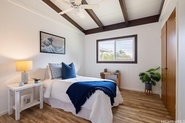 bedroom with ceiling fan, lofted ceiling with beams, baseboards, and wood finished floors