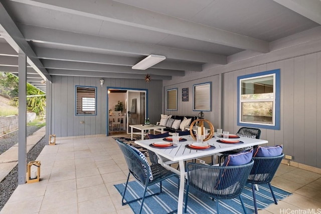 dining space with beam ceiling and light tile patterned flooring