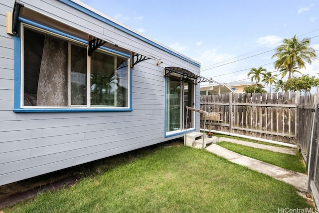 view of property exterior with fence and a lawn