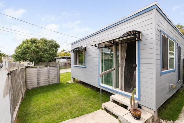 view of side of home with fence and a lawn