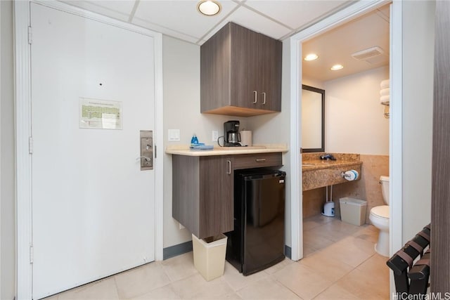 kitchen with light countertops, dark brown cabinetry, visible vents, and light tile patterned floors