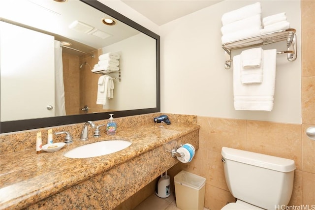 bathroom featuring a wainscoted wall, tile walls, toilet, a sink, and a shower with curtain